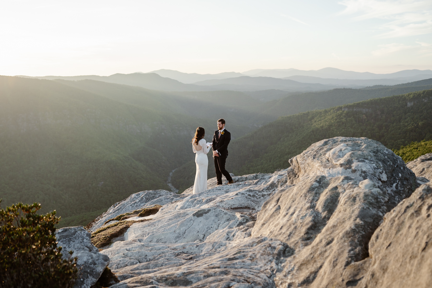 Couple standing on a mountain reading their wedding vows to each other.