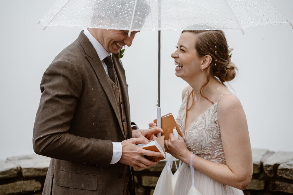 Couple laughing together under an umbrella while saying their vows during their elopement near Asheville, NC