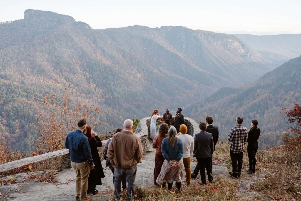 Couple performing a small wedding ceremony with guests at a mountain overlook