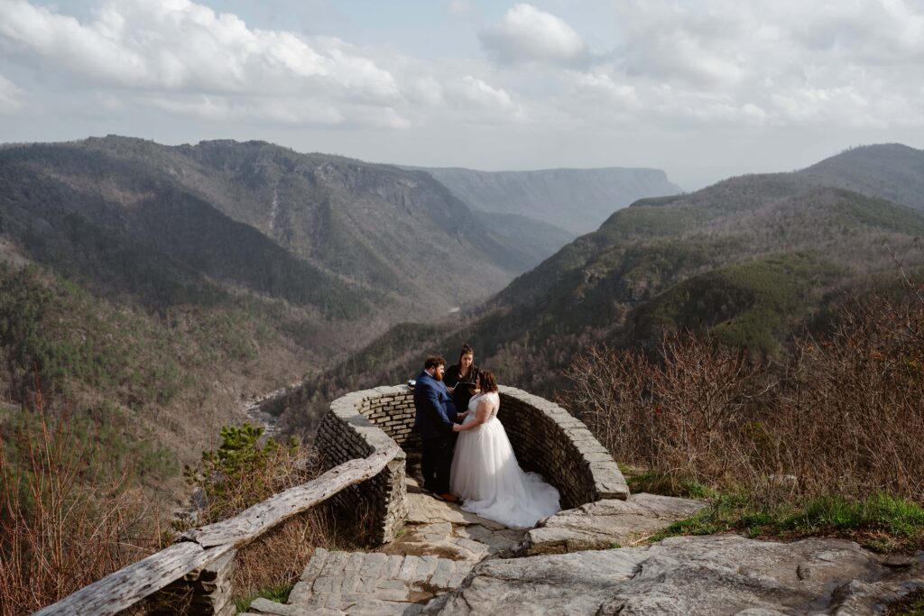 Couple standing at an overlook in the Linville Gorge Wilderness with an officiant during their elopement ceremony